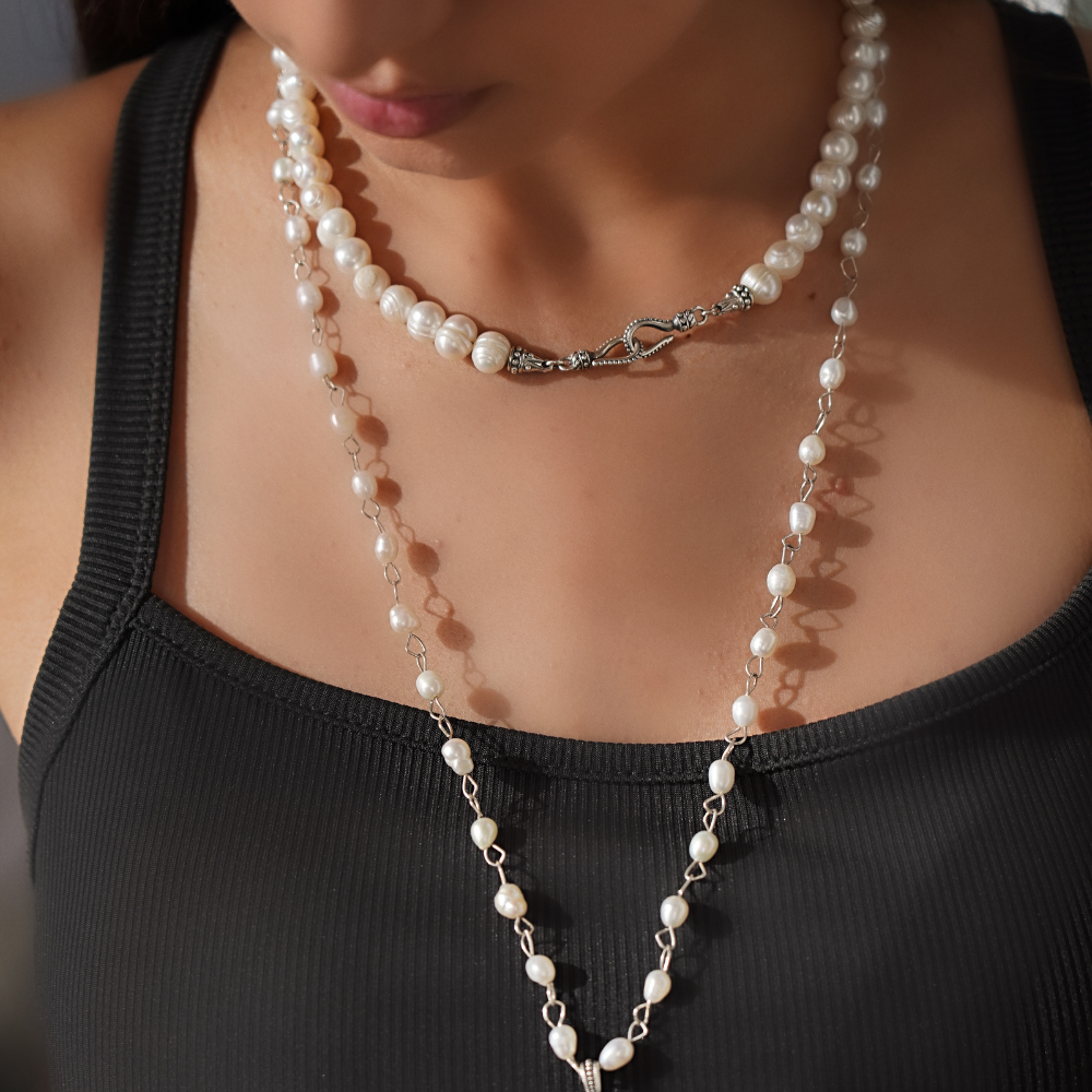 Pearl necklace with silver clasp in ethnic style worn by a person in a black top.