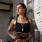 Woman wearing a black top and pearl necklace indoors