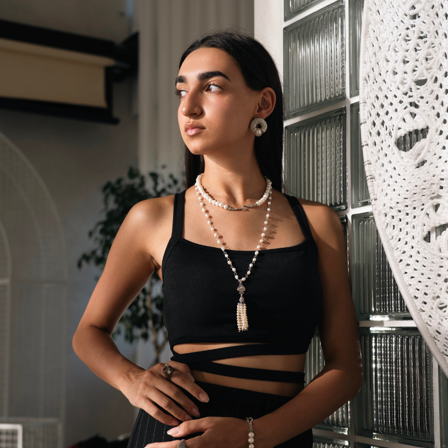 Woman wearing a black top and pearl necklace indoors