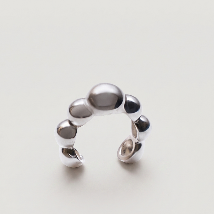 A polished silver cuff with a unique segmented, pebble-like design, photographed on a clean, light off-white background.