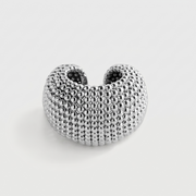 A textured silver ring with a honeycomb or beaded pattern, shown on a light gray background.