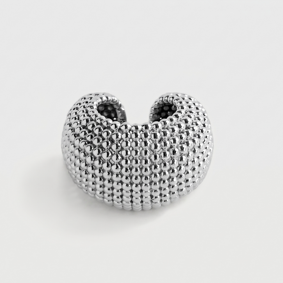 A textured silver ring with a honeycomb or beaded pattern, shown on a light gray background.
