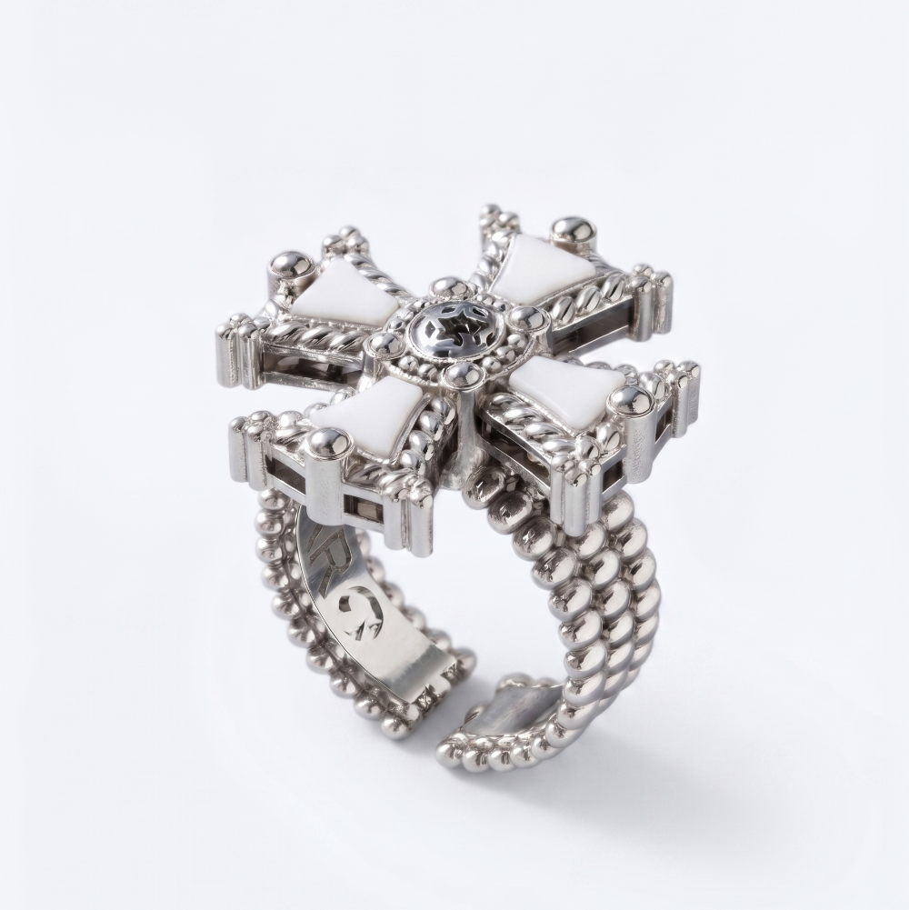 A silver-toned statement ring featuring a decorative cross-shaped top with white inlay sections, a central clear gemstone, and a beaded segmented band, shown on a clean white background.