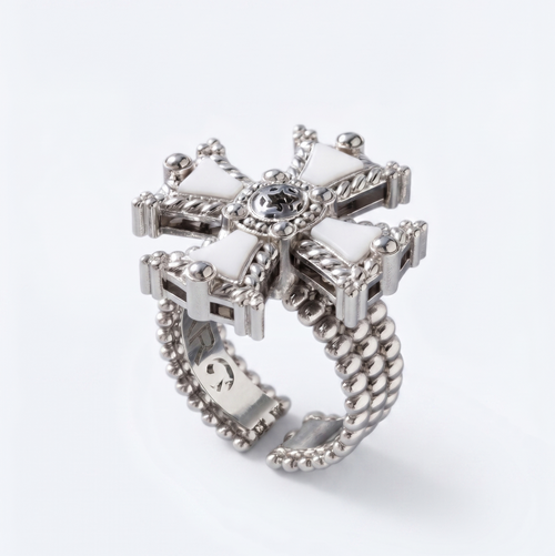 A silver-toned statement ring featuring a decorative cross-shaped top with white inlay sections, a central clear gemstone, and a beaded segmented band, shown on a clean white background.