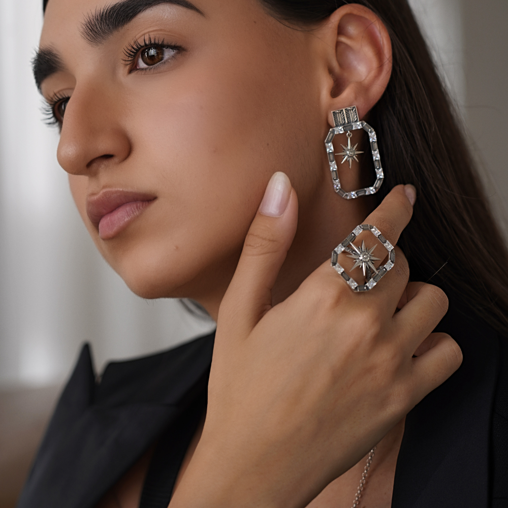 Close-up of a woman wearing silver hoop earrings and a ring with a star design.