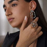 Close-up of a woman wearing silver hoop earrings and a ring with a star design.
