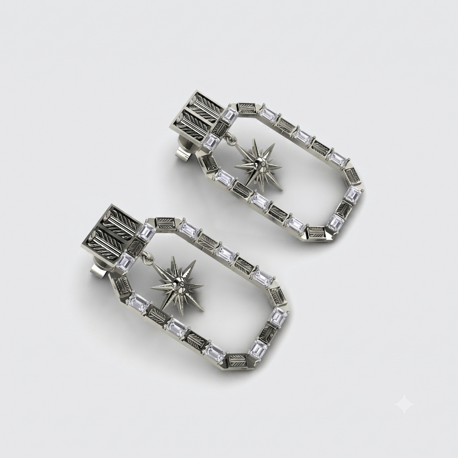 A pair of silver-toned geometric drop earrings with clear faceted stones and starburst center details, displayed on a light gray background.