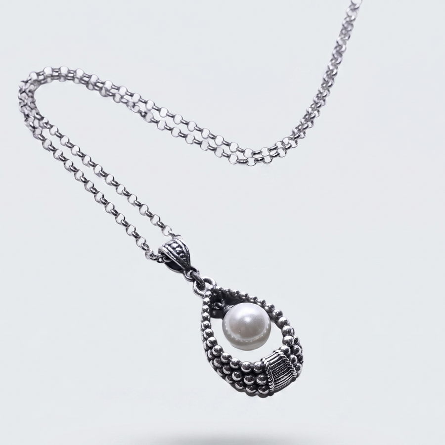 A silver-toned beaded chain necklace with a teardrop-shaped pendant featuring a central white pearl, shown on a light gray background.