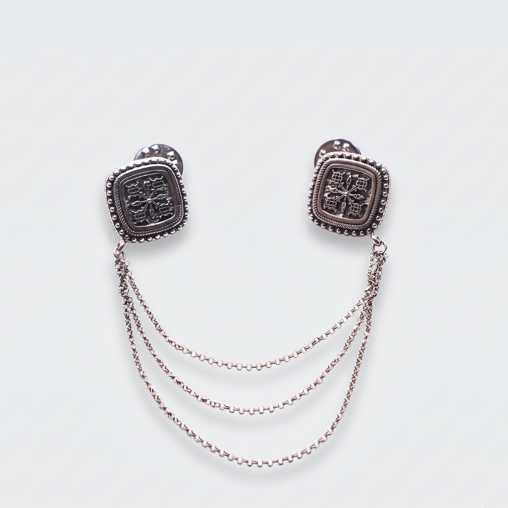 A pair of silver-toned square stud earrings with textured center details and three draped chain links hanging between the studs, shown on a light gray background.