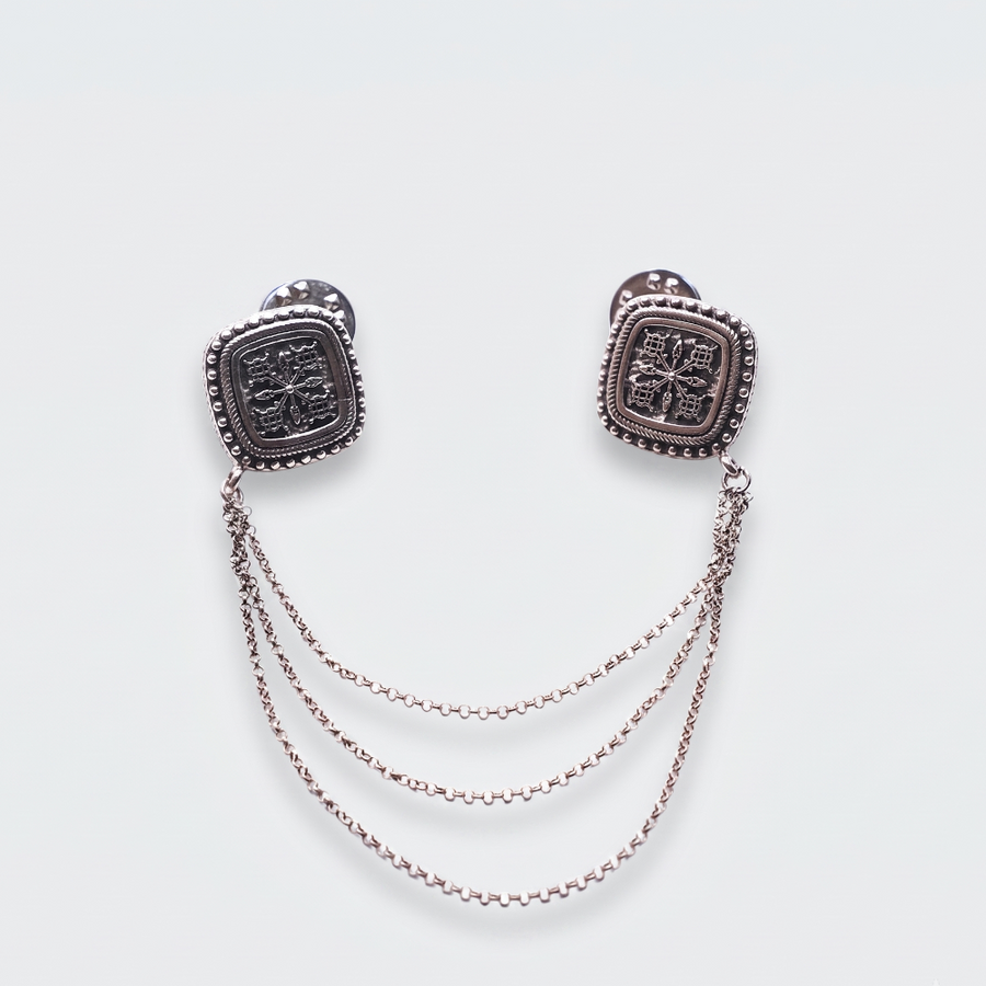 A pair of silver-toned square stud earrings with textured center details and three draped chain links hanging between the studs, shown on a light gray background.