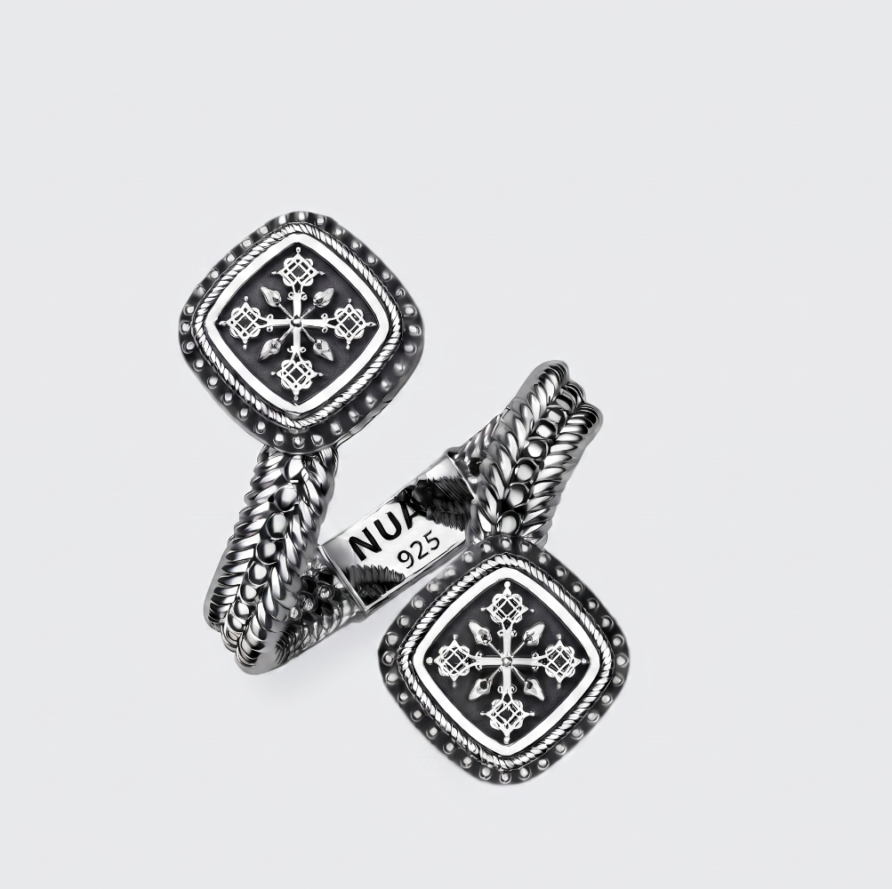 A pair of silver-toned cufflinks with square medallion faces, intricate geometric patterns, and twisted rope-like bands, displayed on a light gray background. One cufflink shows a 'NU 925' hallmark.