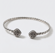 A silver-toned twisted cable cuff bracelet with two square pavé-set bezel stones, photographed on a clean white background.