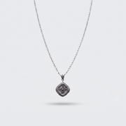 A silver-toned chain necklace with a square pendant featuring an intricate floral or starburst pattern, shown against a light gray background.