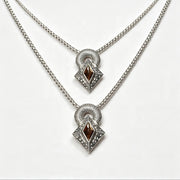 A pair of silver-tone layered necklaces with diamond-shaped pendants featuring dark brown gemstone centers and clear accent stones, displayed on a clean white background.