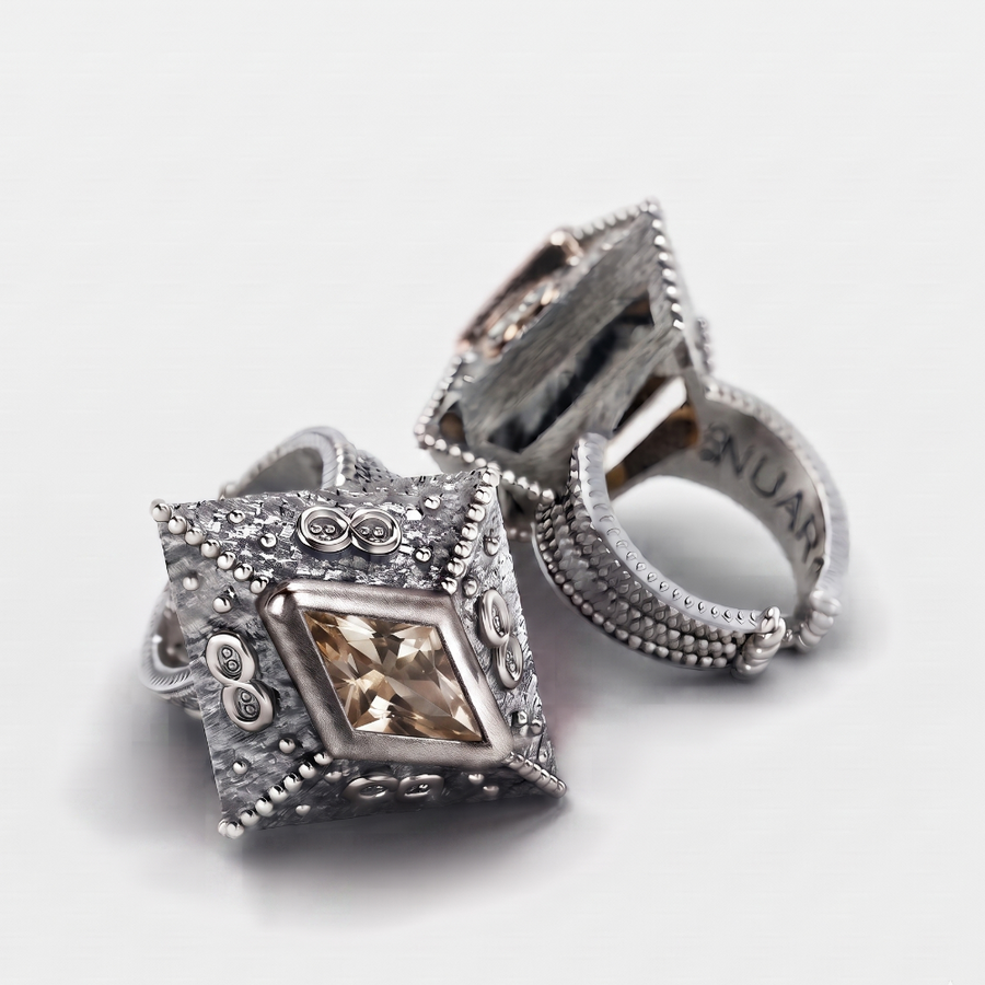A pair of silver-toned vintage-style ring pullers with a central diamond-cut champagne-colored gemstone and ornate textured detailing, shown on a light gray background.