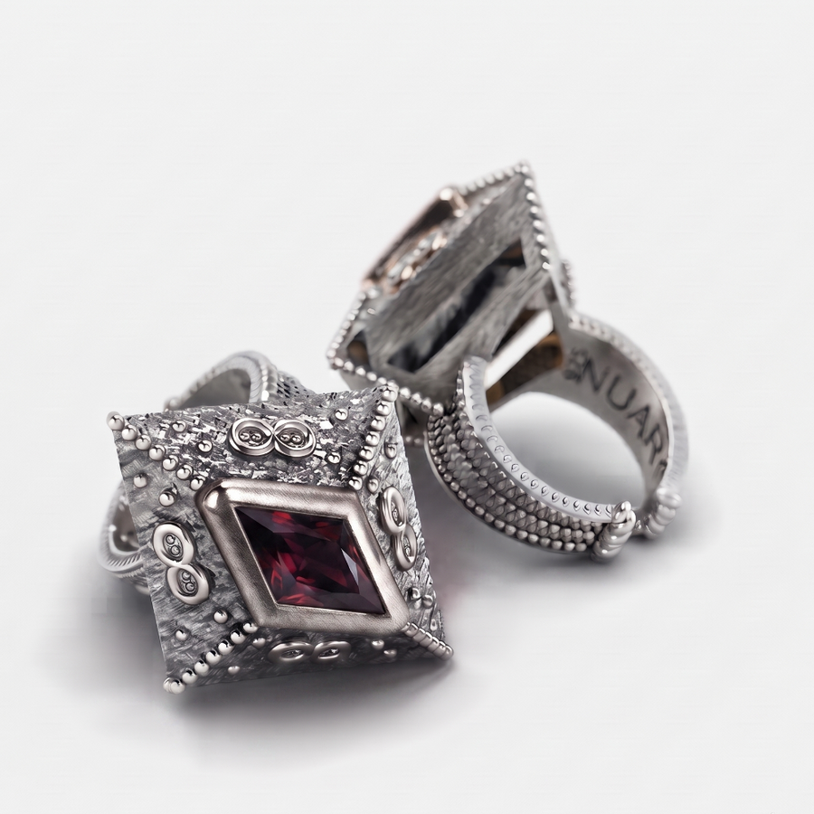 A pair of silver-toned vintage-style ring stands with ornate beaded borders and a central rectangular red gemstone, photographed on a clean white background.