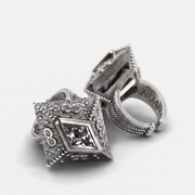 A pair of silver-toned vintage-style cufflinks with ornate beaded borders and a central clear faceted gemstone, shown on a light gray background.
