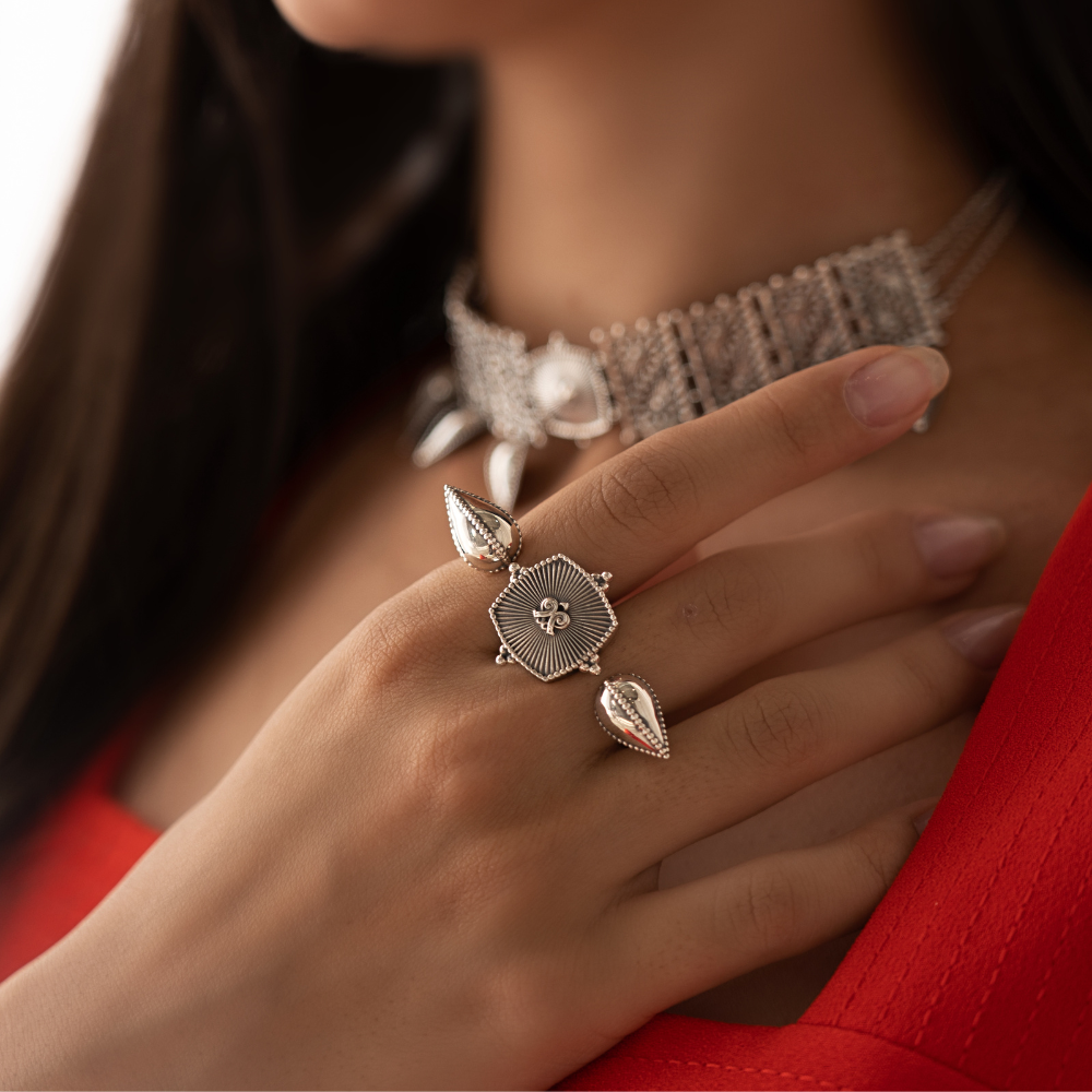 Close-up of a hand wearing massive silver rings with a blurred background