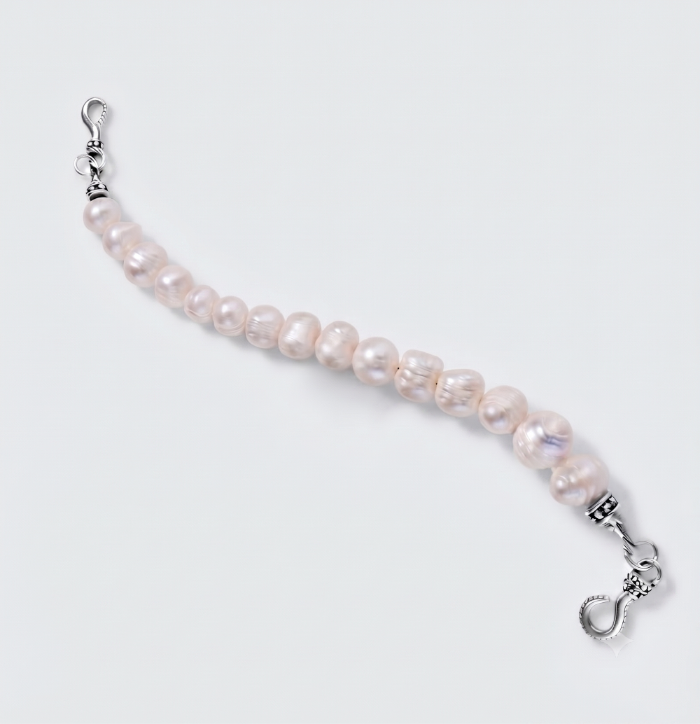 A beaded bracelet featuring irregular, lustrous light pink freshwater pearls strung on a silver-tone cord, finished with silver lobster clasps on both ends, shown on a light gray background.