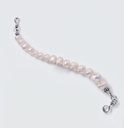 A beaded bracelet featuring irregular, lustrous light pink freshwater pearls strung on a silver-tone cord, finished with silver lobster clasps on both ends, shown on a light gray background.