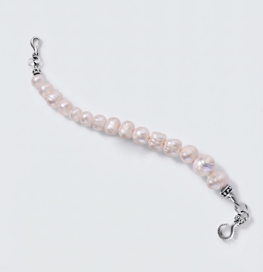 A beaded bracelet featuring irregular, lustrous light pink freshwater pearls strung on a silver-tone cord, finished with silver lobster clasps on both ends, shown on a light gray background.