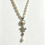 A pearl and silver pendant necklace featuring a central round pearl, a silver Maltese cross, a small star, and a dangling pearl bead, displayed on a plain white background.