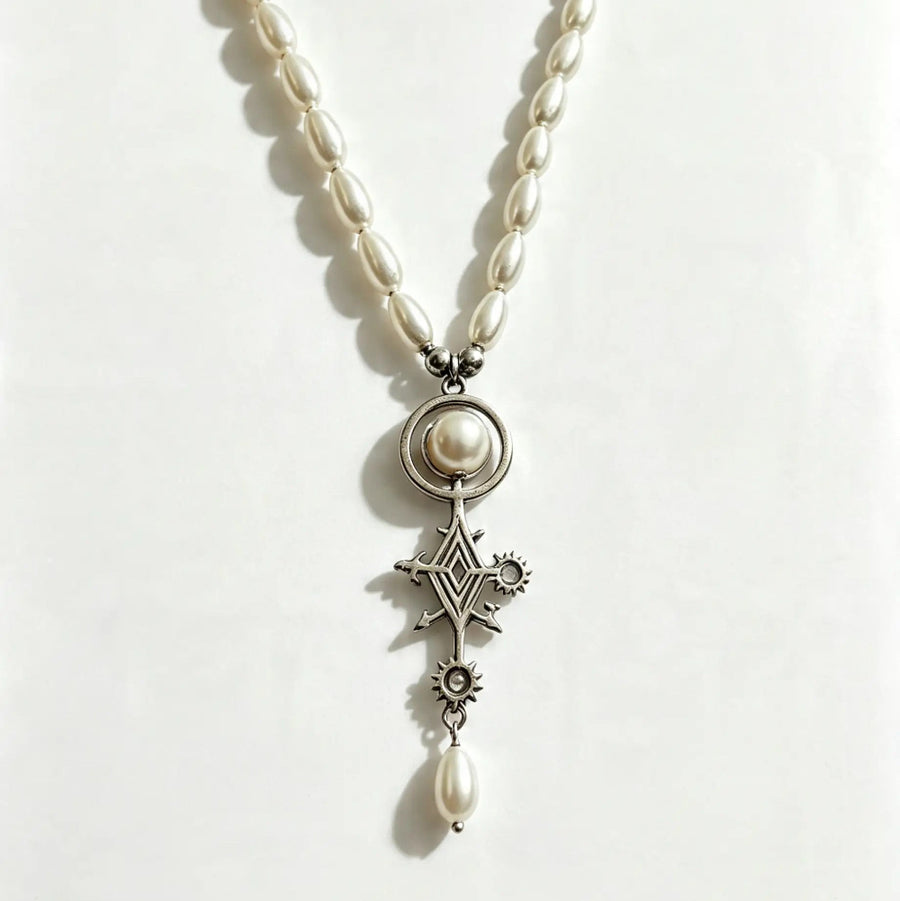 A pearl and silver pendant necklace featuring a central round pearl, a silver Maltese cross, a small star, and a dangling pearl bead, displayed on a plain white background.