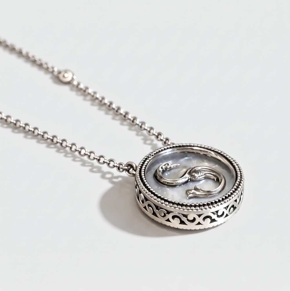 A silver pendant necklace featuring a circular filigree frame and a central raised symbol resembling a stylized snake or knot, shown on a clean white background.