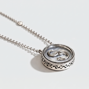A silver pendant necklace featuring a circular filigree frame and a central raised symbol resembling a stylized snake or knot, shown on a clean white background.