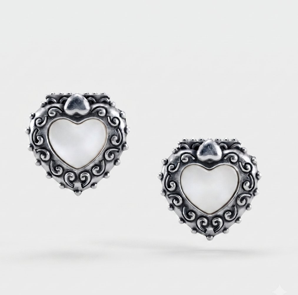 A pair of silver heart-shaped earrings with ornate scrollwork borders and white mother-of-pearl centers, shown on a light gray background.