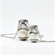 Two silver urn-style pendant necklaces with white pearl-like beads, displayed on a clean white background.