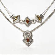 A silver-tone double-strand necklace featuring three diamond-shaped motifs with amber-brown gemstones and clear crystals, with a matching pendant hanging below on a white background.