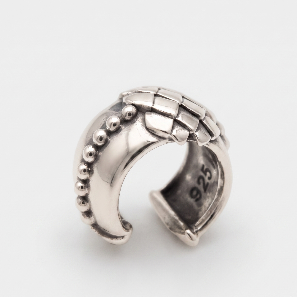 A sterling silver curved ring with a textured basketweave pattern on the top and a row of small raised beads on one side, photographed on a clean light gray background.