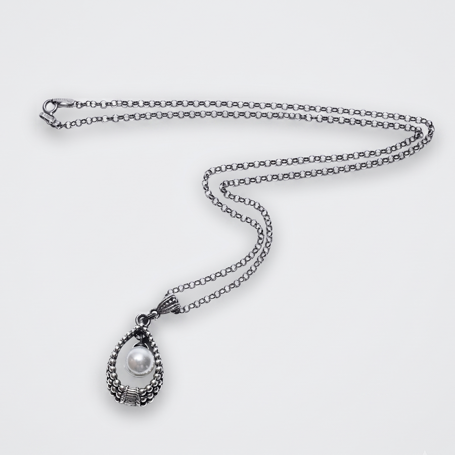 A silver teardrop pendant necklace featuring a textured silver frame and a central white pearl, displayed on a clean light gray background.