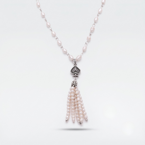 A silver-toned necklace featuring a beaded chain with small pale pink pearls, a silver lotus-shaped pendant, and a dangling tassel made of multiple strands of pale pink pearls, shown on a light gray background.