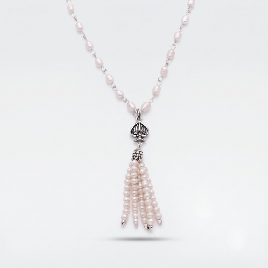 A silver-toned necklace featuring a beaded chain with small pale pink pearls, a silver lotus-shaped pendant, and a dangling tassel made of multiple strands of pale pink pearls, shown on a light gray background.