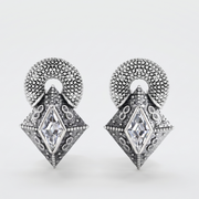 A pair of silver-toned drop earrings with a textured circular top and a faceted diamond-shaped pendant featuring a central clear gemstone, shown on a light gray background.