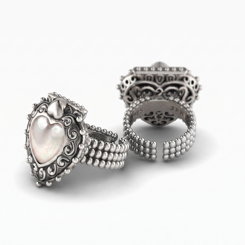 Three silver rings displayed on a clean white background, including a heart-shaped ring with a mother-of-pearl center and two open band rings with intricate filigree detailing.