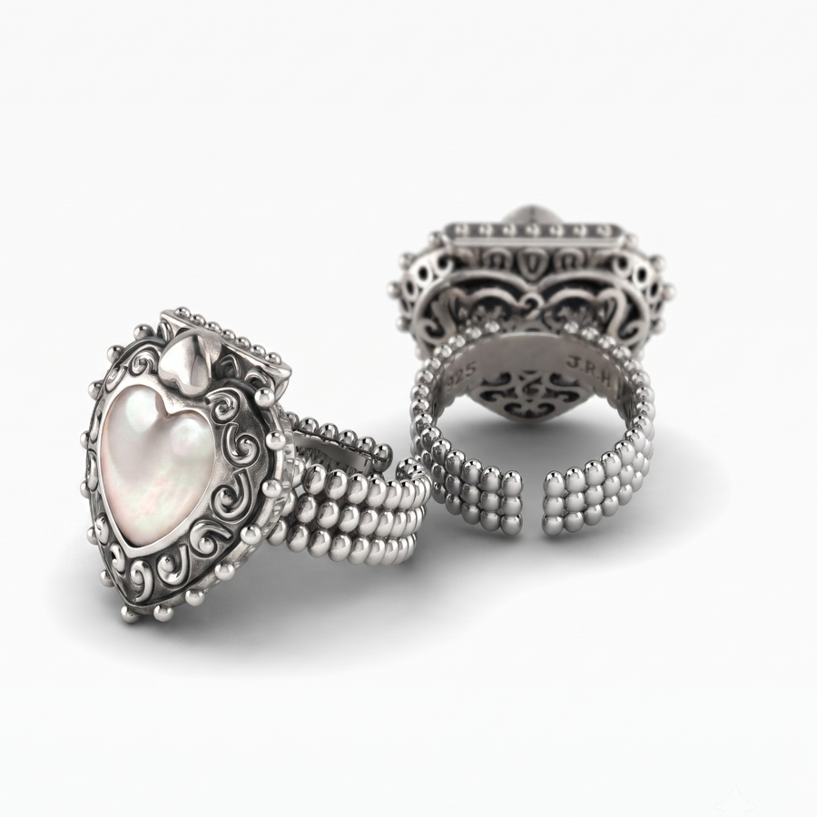 Three silver rings displayed on a clean white background, including a heart-shaped ring with a mother-of-pearl center and two open band rings with intricate filigree detailing.