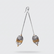 A pair of dangling earrings with long silver-tone wire stems and acorn-shaped drops. The acorns are textured with silver pavé stones and a band of gold-tone detailing, shown against a light gray background.