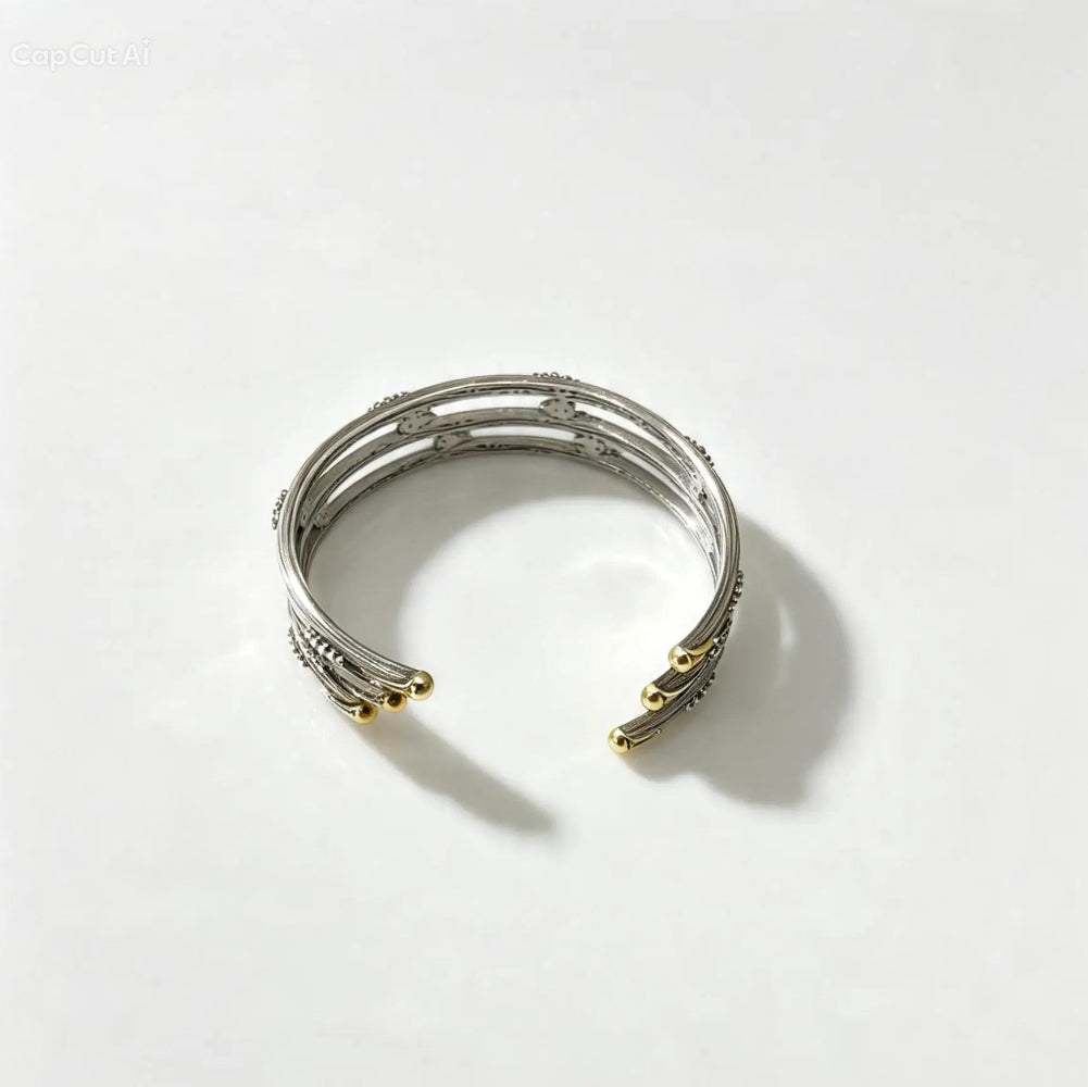 A silver-toned multi-band cuff bracelet with small gold-toned accents at the ends, photographed on a clean white background.