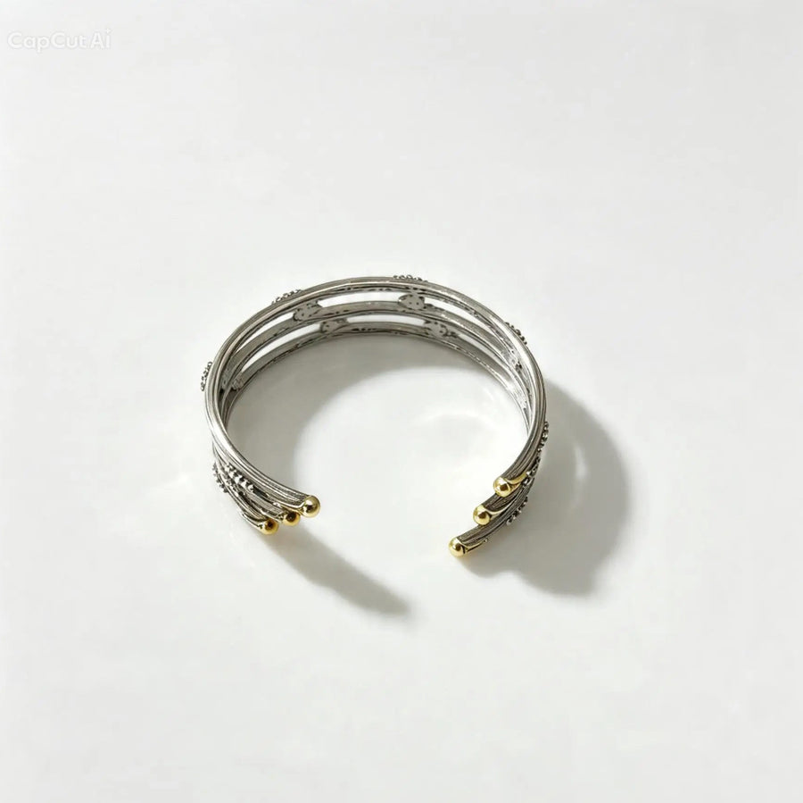 A silver-toned multi-band cuff bracelet with small gold-toned accents at the ends, photographed on a clean white background.