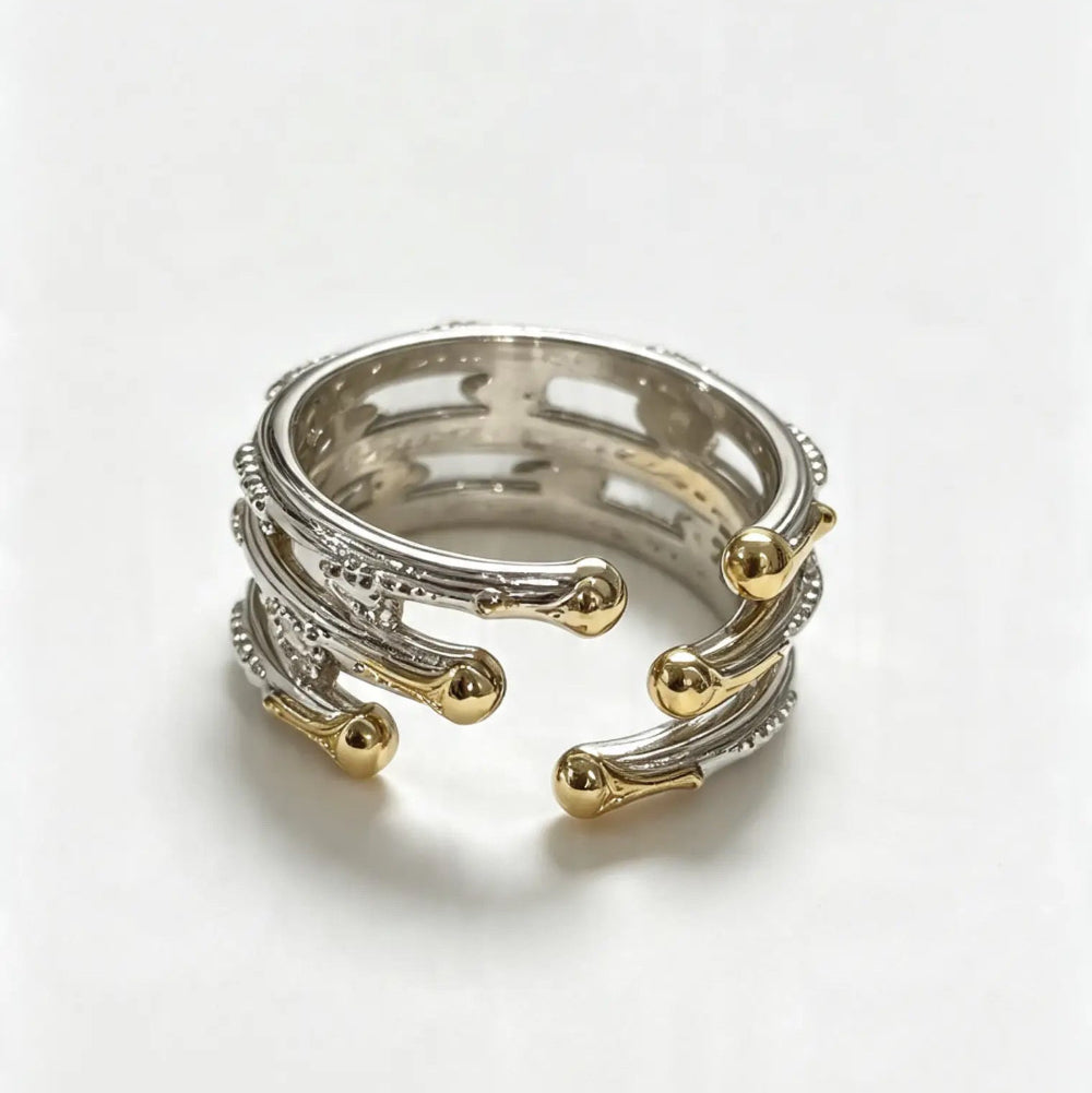 A two-tone silver and gold open wrap ring with textured details and small gold bead accents, photographed on a clean white background.
