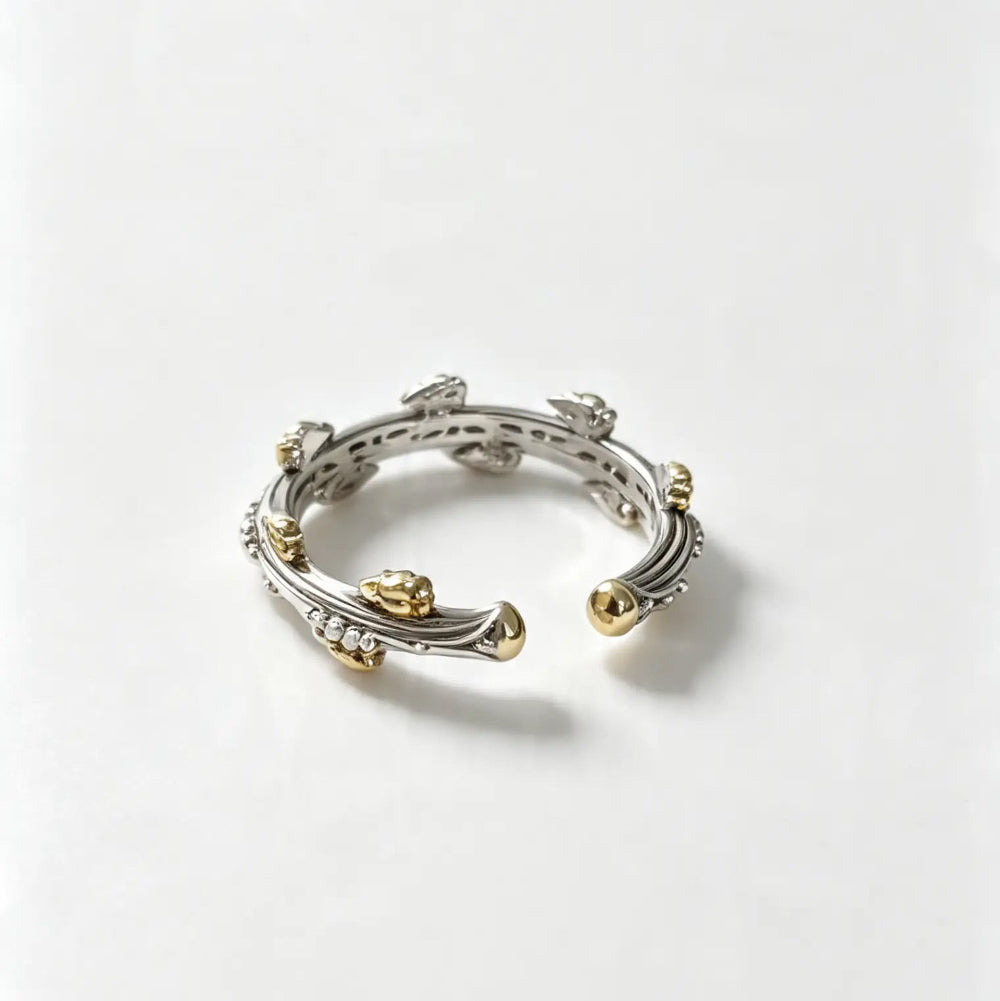 A delicate two-tone silver and gold bangle bracelet with small gold lion head accents and tiny clear stones, displayed on a clean white background.