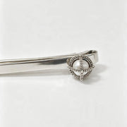 A silver-toned metal tie clip with a decorative circular head featuring a central white pearl and small clear stones, shown on a plain white background.