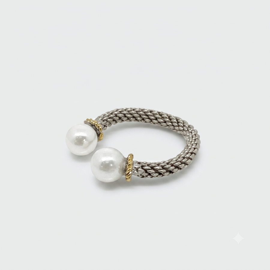 A silver-toned twisted rope ring with two white pearl beads and small gold-toned spacer details, photographed on a clean light gray background.