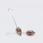 A pair of dangling earrings with textured metallic acorn-shaped beads, one in silver and one in rose gold, suspended from thin silver wire hooks on a light gray background.